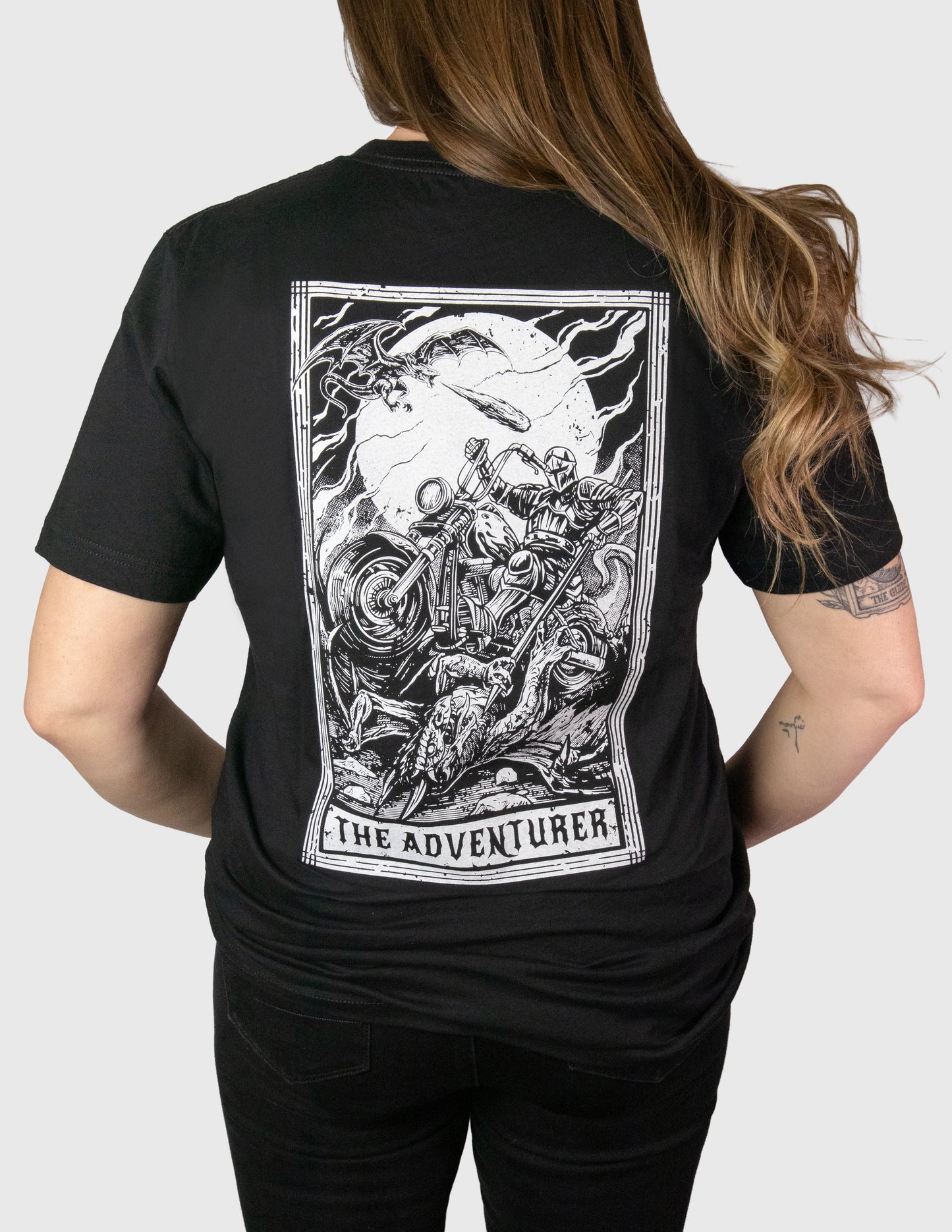 Woman wearing a black t-shirt with a graphic design on the back, set against a plain background. Her Two Wheels