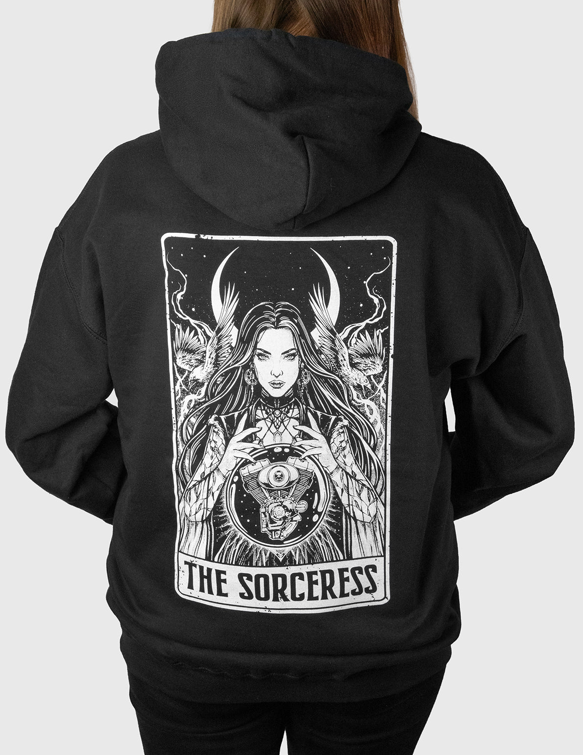 Black hoodie with 'The Sorceress' design on the back, worn by a Woman.